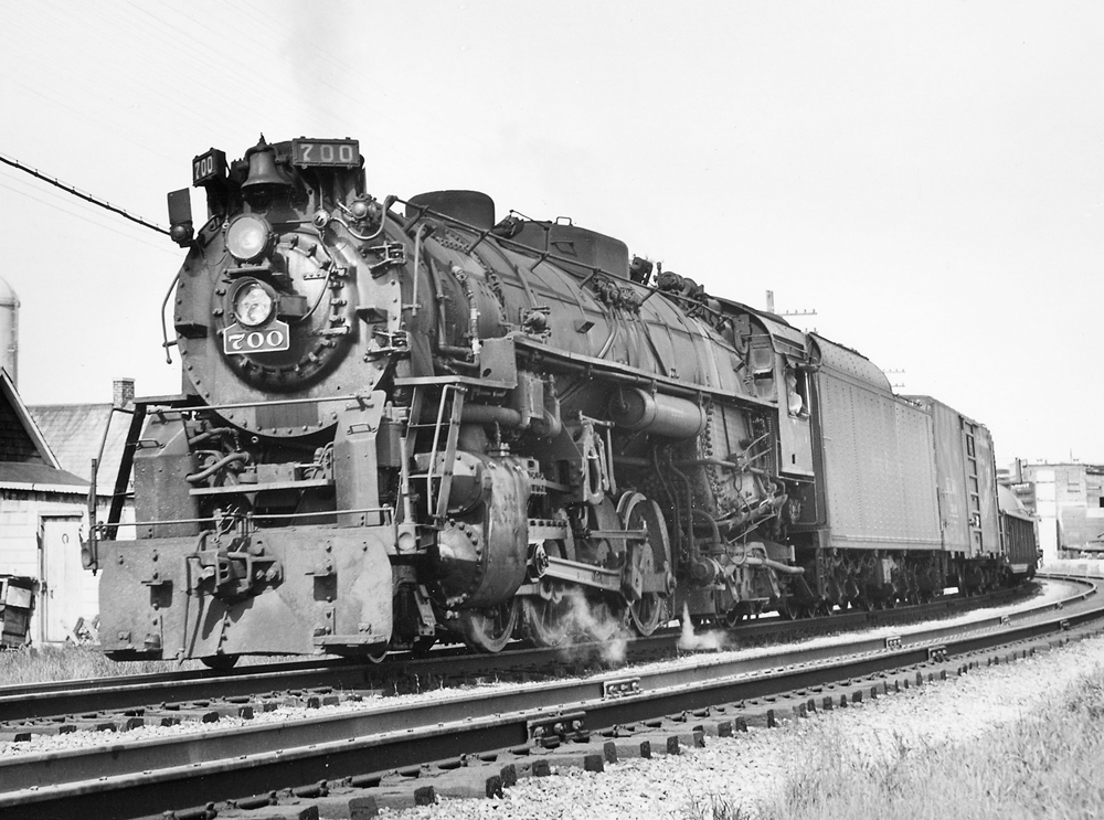 A close up black and white photo of a 2-8-4 fast freight steam locomotive moving on the tracks