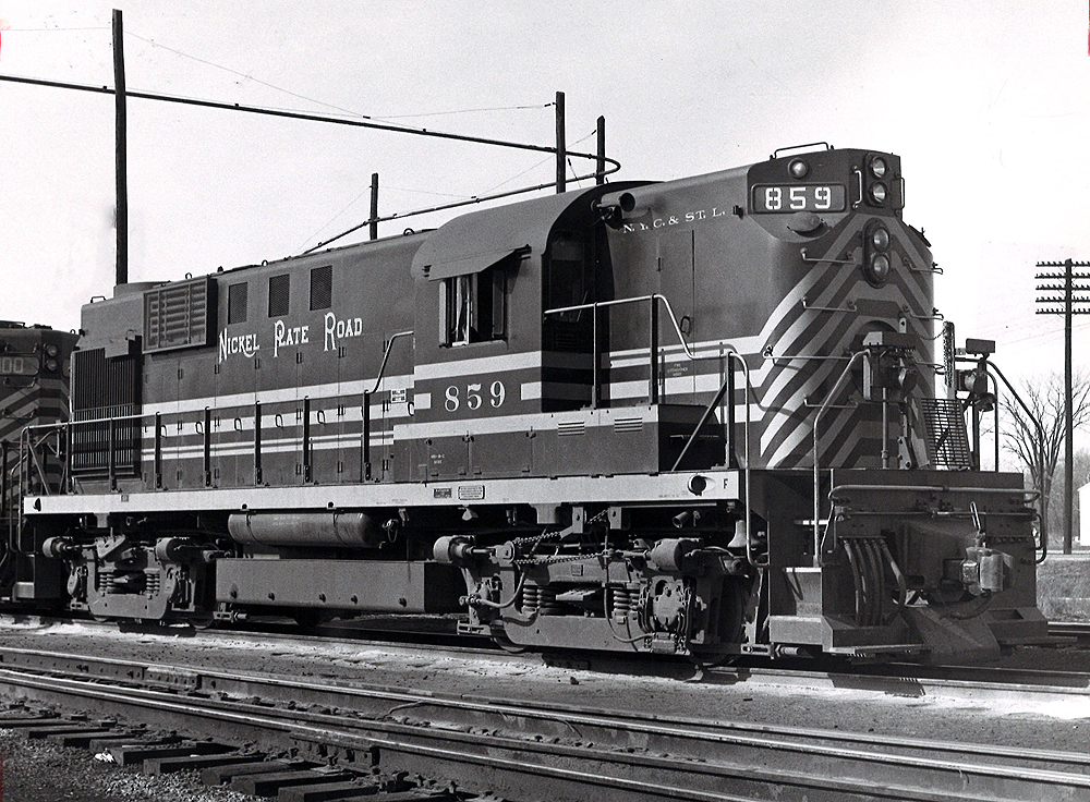A close up black and white photo of a road-switcher diesel locomotive in a rail yard