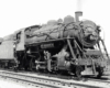 A close up black and white photo of a 2-8-0 Consolidation-type steam locomotive with the conductor looking out the window