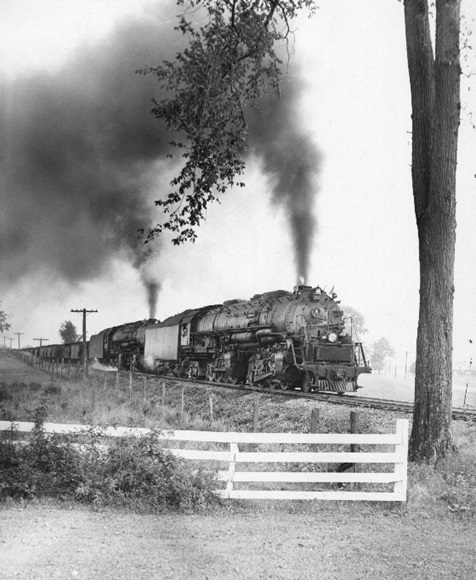 A train passing by a fenced in yard