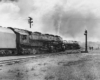 A train passing by a stop light and two people walking