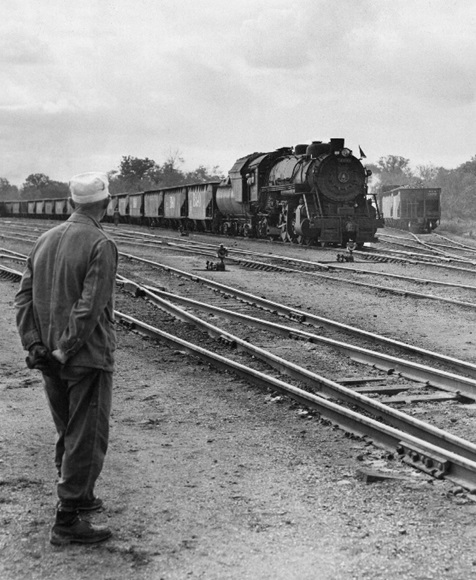 A man standing, looking at a train