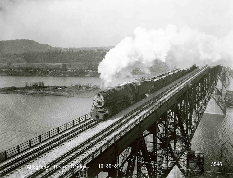 Steam locomotive with train on deck truss bridge