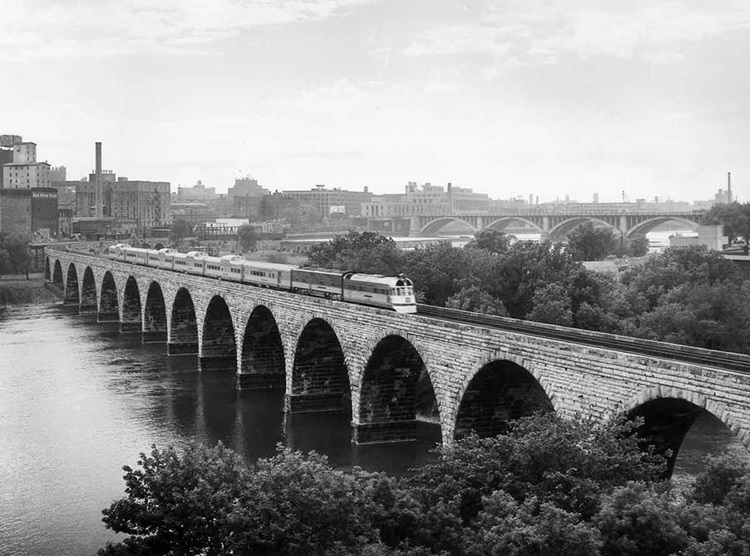 Streamlined passenger train on stone arch bridge
