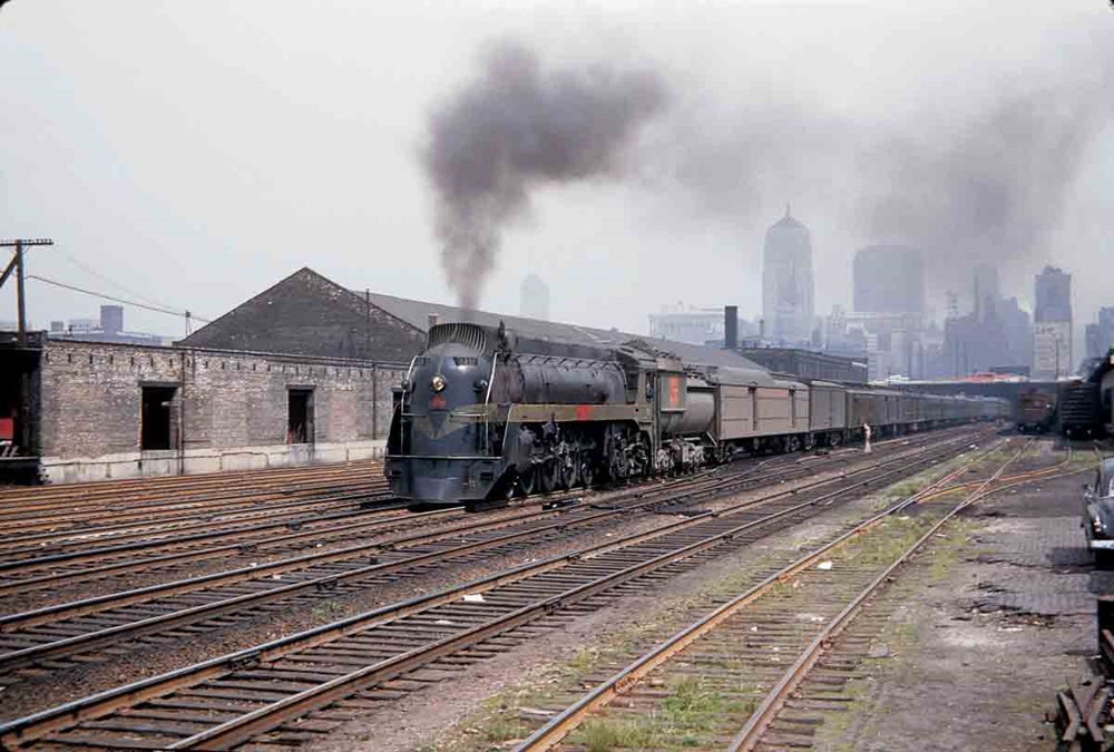 a streamliner pulling passenger cars with chicago in the background