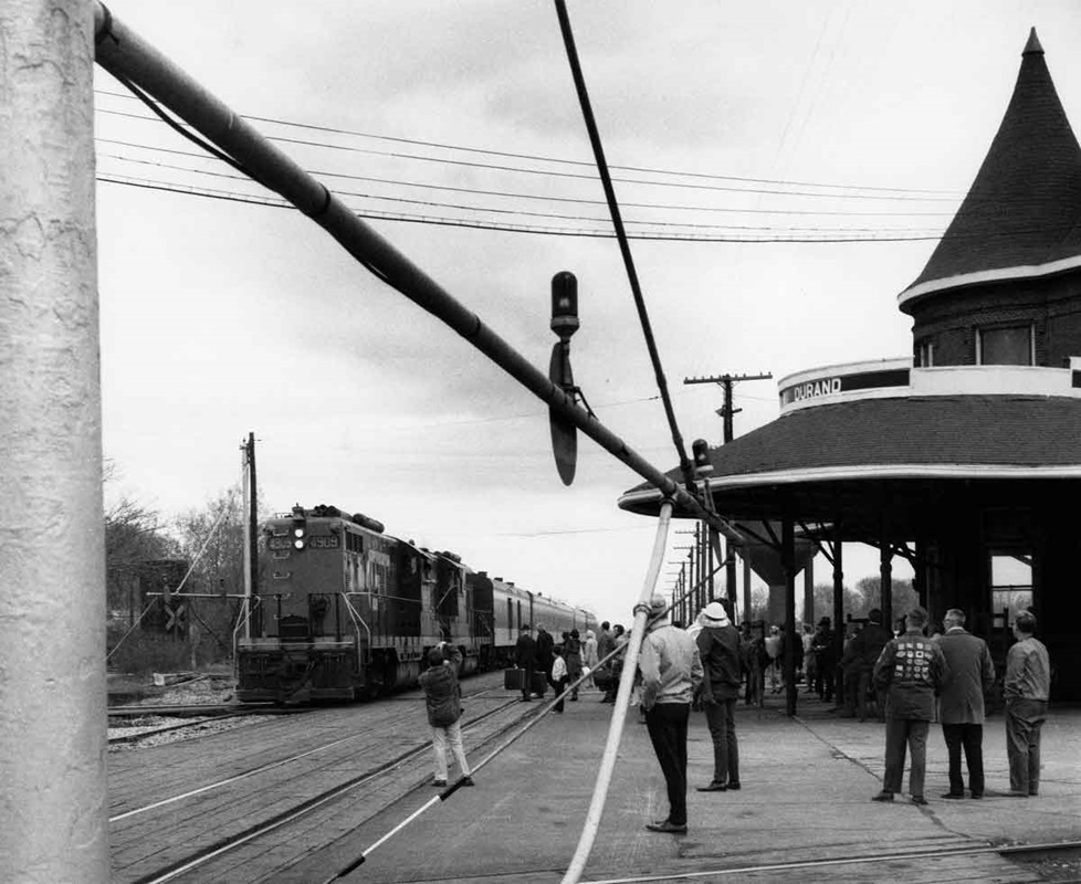 people waiting to board a passenger train at a station