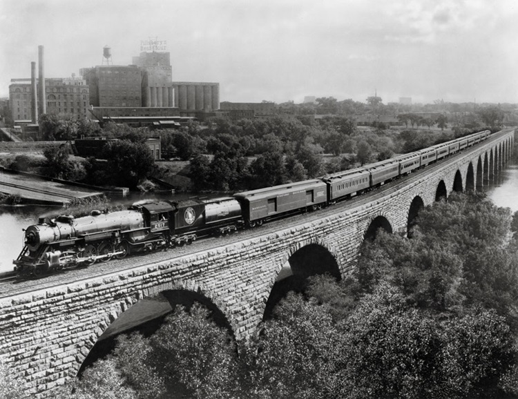 Steam powered passenger train on stone arch bridge