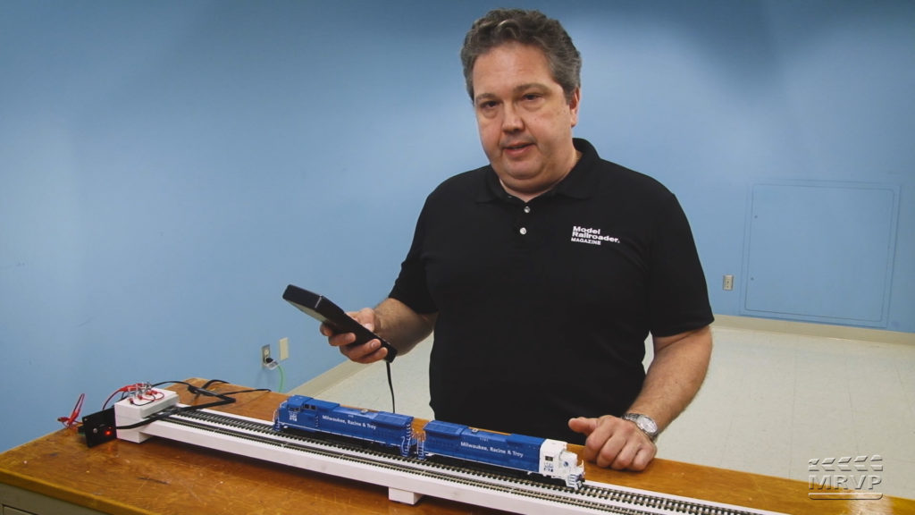 Dana Kawala running locomotives on a test track and holding a throttle.