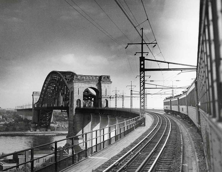 Passenger cars curve around large bridge