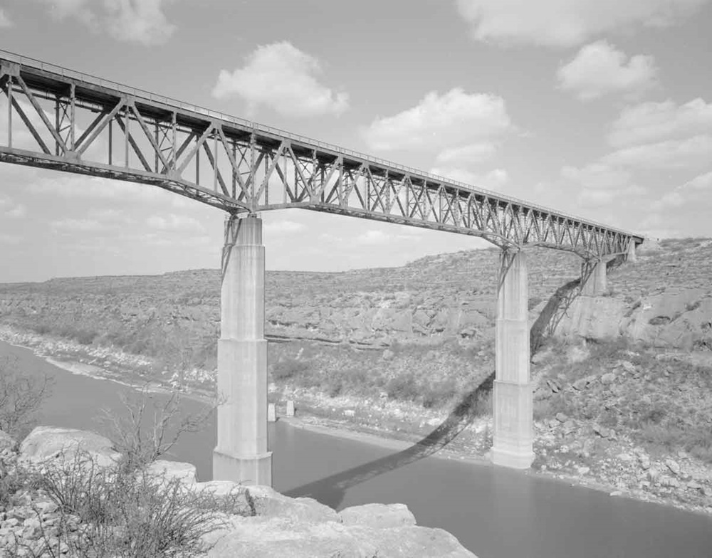 Deck truss bridge with concrete piers over canyon