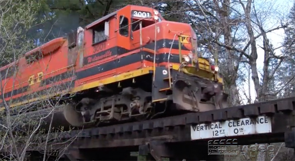 Close-up image of an orange-painted diesel locomotive on a trestle.