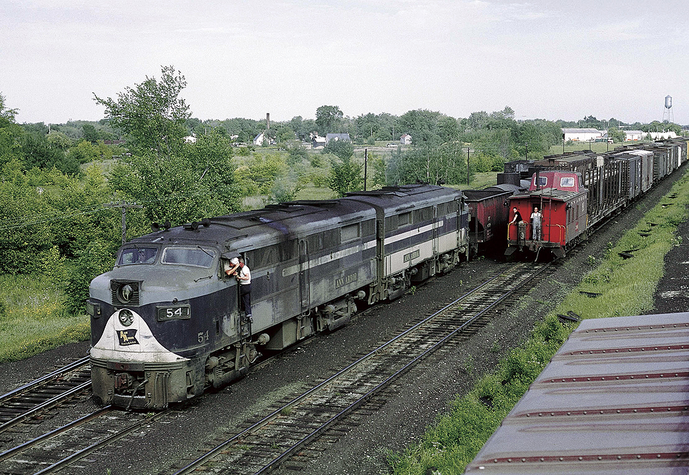 Two cab-style diesel locomotives with freight train being passed by caboose of second freight train
