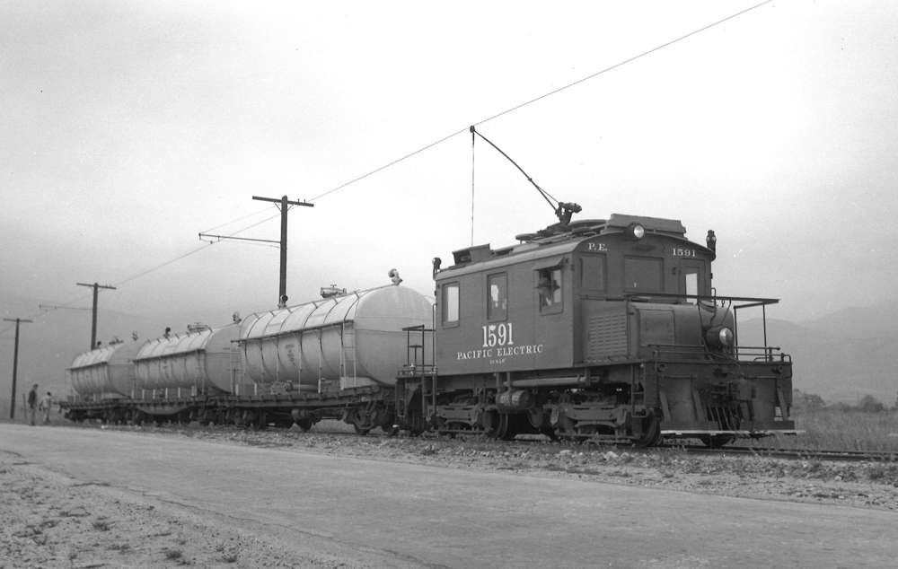 Freight motor hauls three water tank cars.