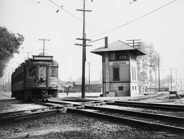 Streetcar or electric interurban car about to cross a double-diamond overlooked by an interlocking tower.