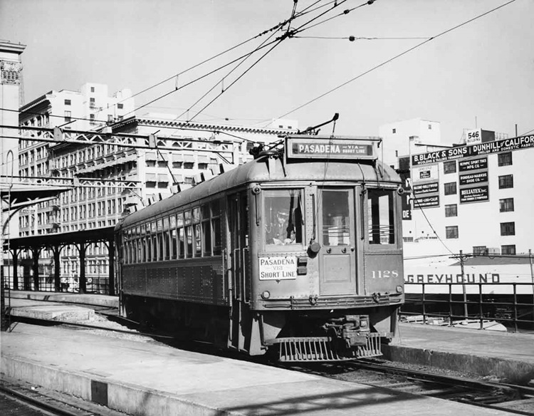 Streetcar departs a terminal on elevated tracks in a city scene.