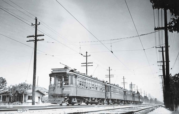Five connected streetcars or electric interurbans caught moving with a motion-blurred photograph.