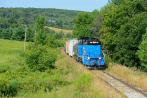 Blue train traveling down tracks