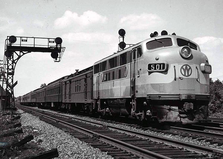 One cab unit diesel locomotive leads a passenger train over a multi-track mainline.