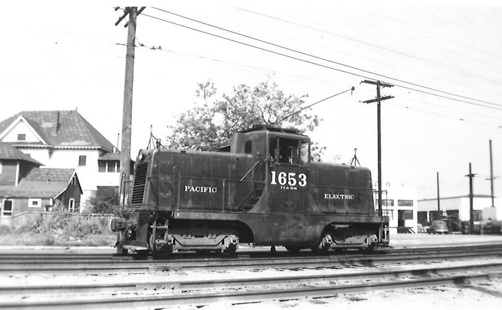 A center cab diesel locomotive appears on a multi-track mainline.