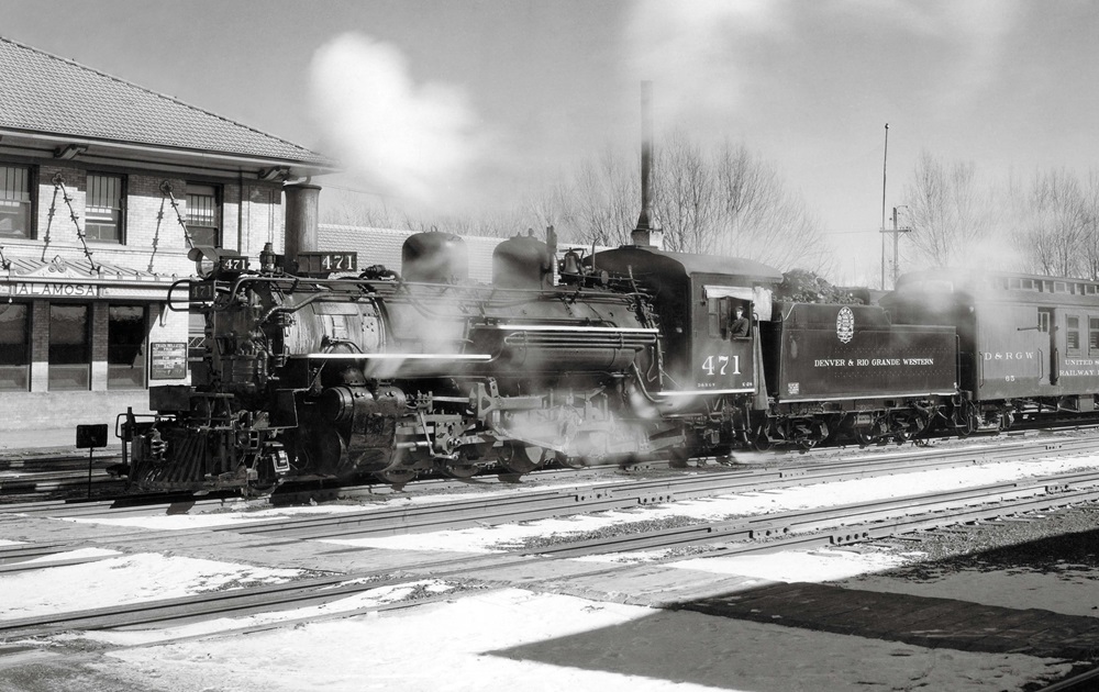 Smoking steam locomotive in front of station