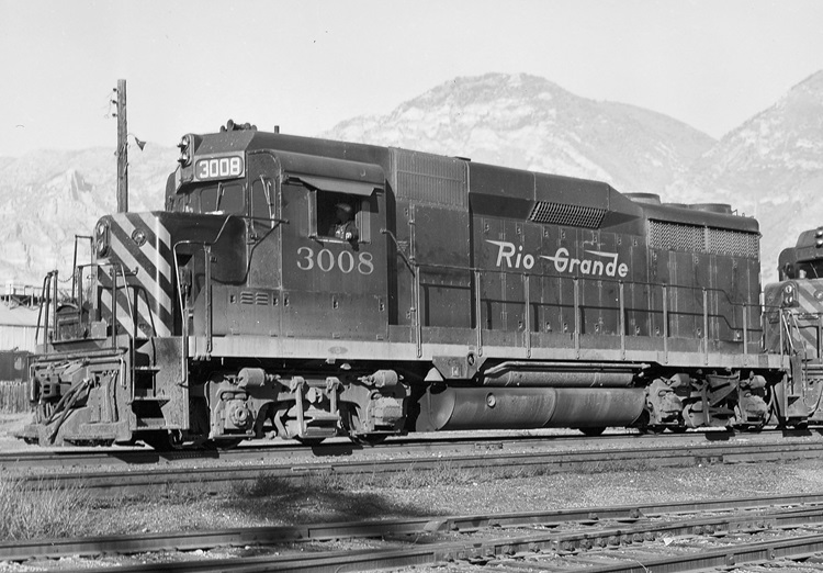 Side view of a four-axle diesel locomotive with mountains in the background.