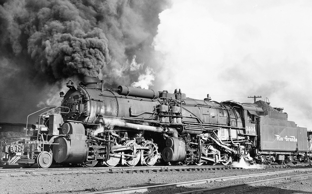 Side view of a 2-8-8-2 steam locomotive with a large smoke plume.