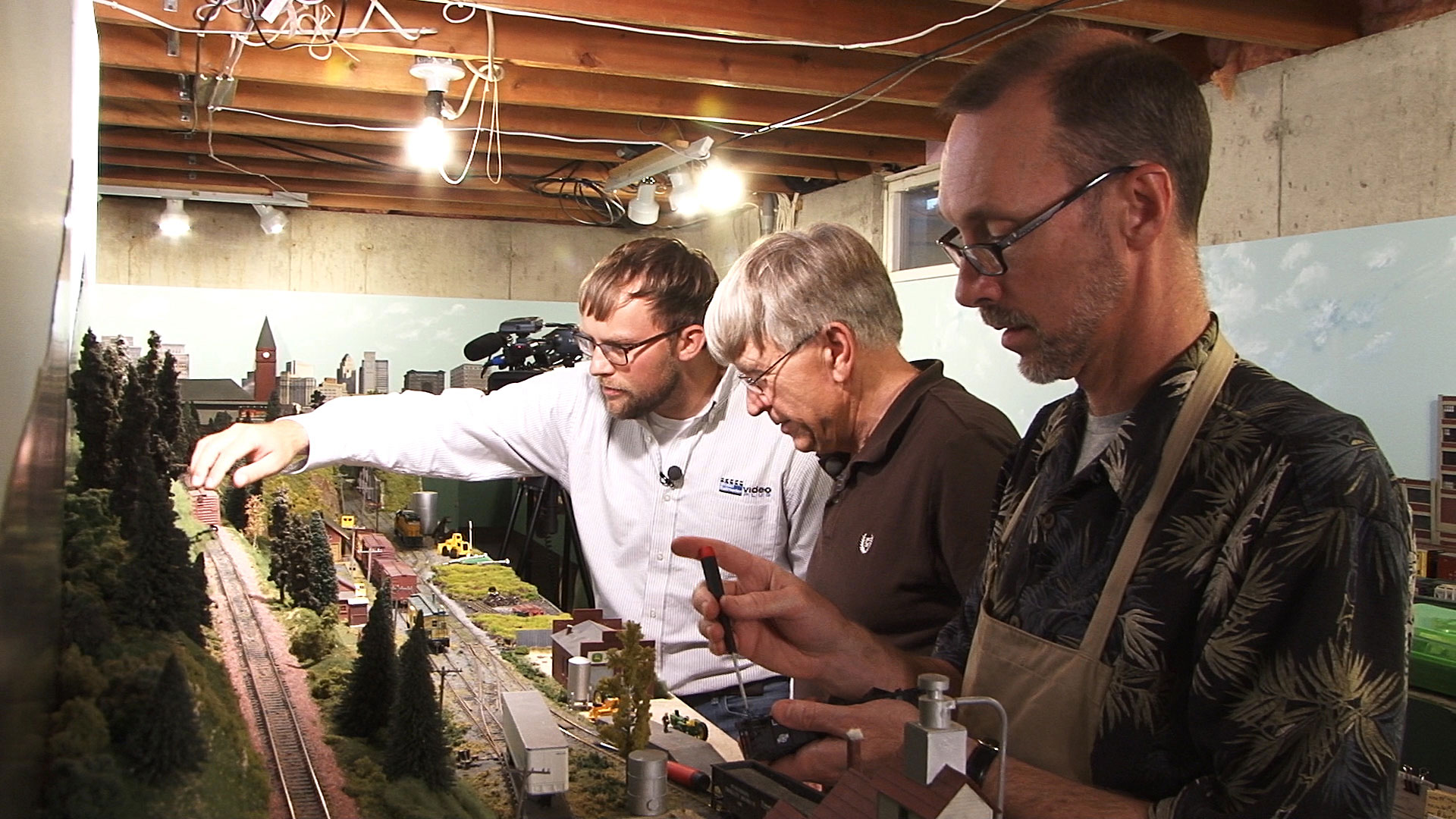 Three people from a model railroader club working together on a layout