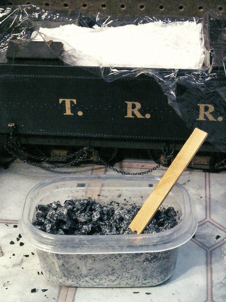 Diluted white glue is mixed with crushed coal to become a load on a model steam locomotive tender.