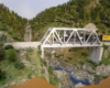 A double-tracked bridge hosts a steam-locomotive hauled Santa Fe train over a green-and-rock filled gorge.