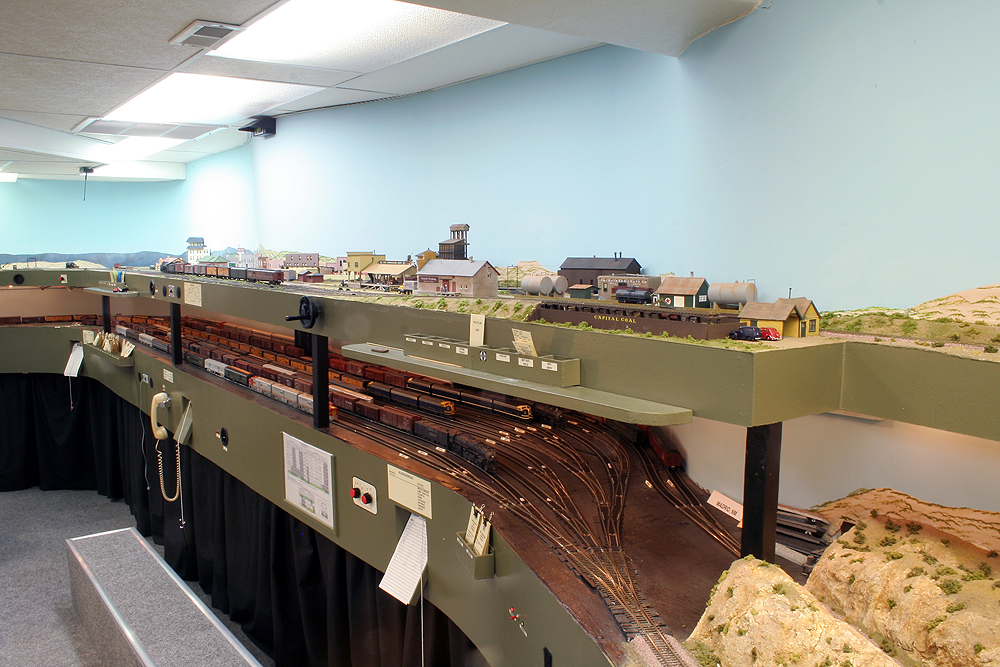 A visitor's view of a double-deck Santa Fe layout with scenery on top and a staging yard below.