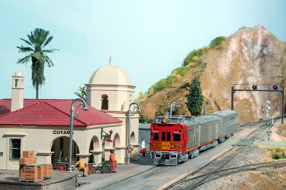 A Santa Fe doodlebug and passenger car pause in front of a scratch-built passenger station.