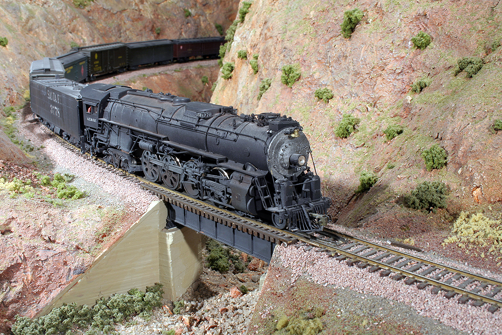 Close-up shot of an HO Scale 4-8-4 Santa Fe steam locomotive hauling an express train through a gorge.
