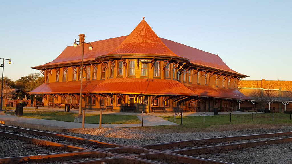 An old-style rounded train station at a diamond in low-angle sunlight under clear skies.