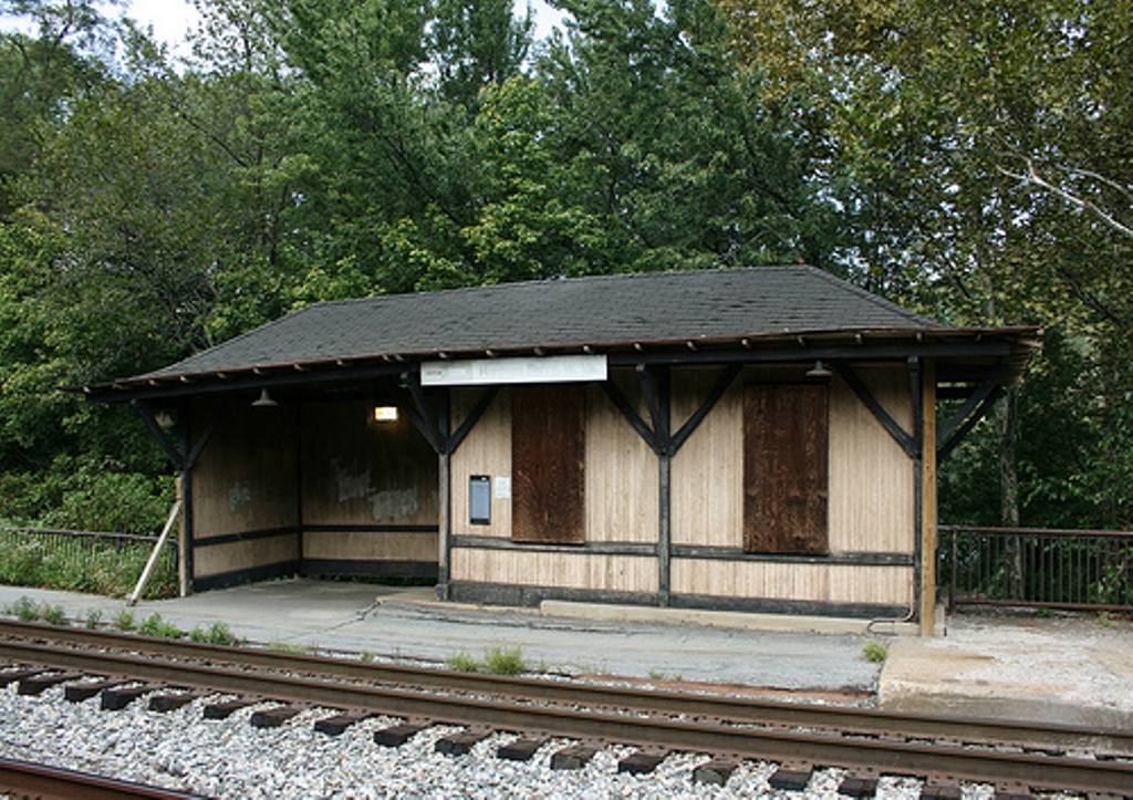 A dilapidated wood shelter next to railroad tracks.