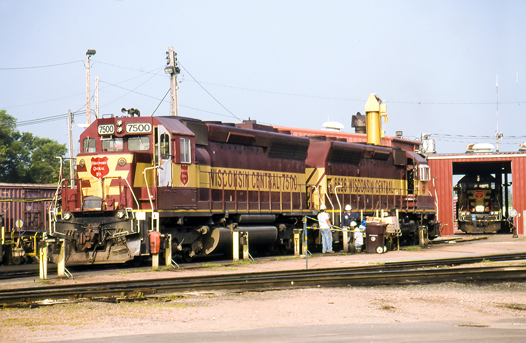 Crimson and yellow-striped locomotives under sunny skies.