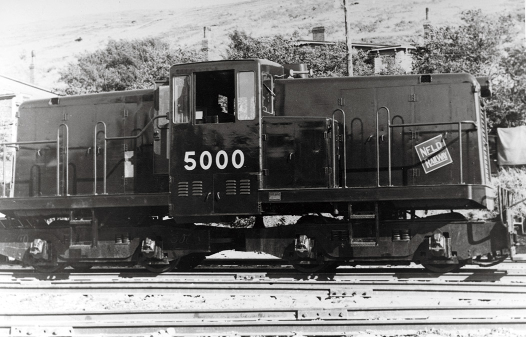 Center-cab diesel electric locomotive seen in at rest in a rail yard.