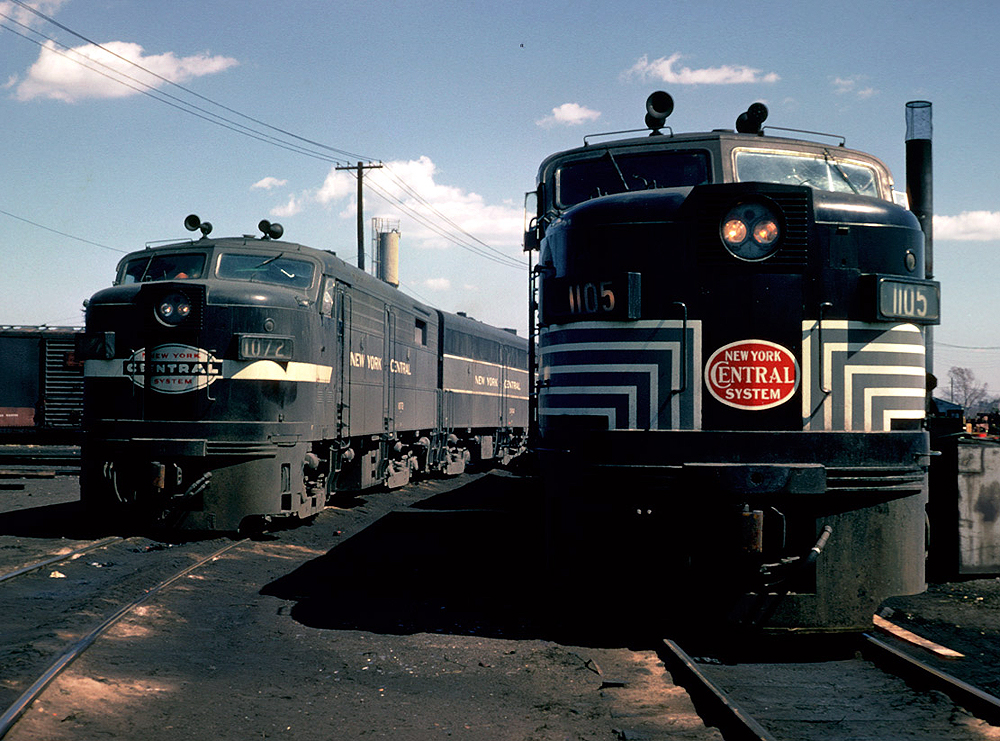 Two cab unit-style diesel locomotives appear in a rail yard.