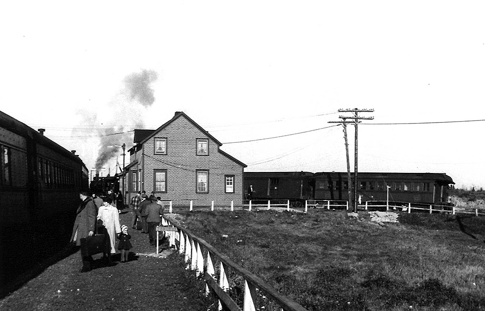 Two trains on separate, converging tracks appear in one view with a house like structure at the apex.