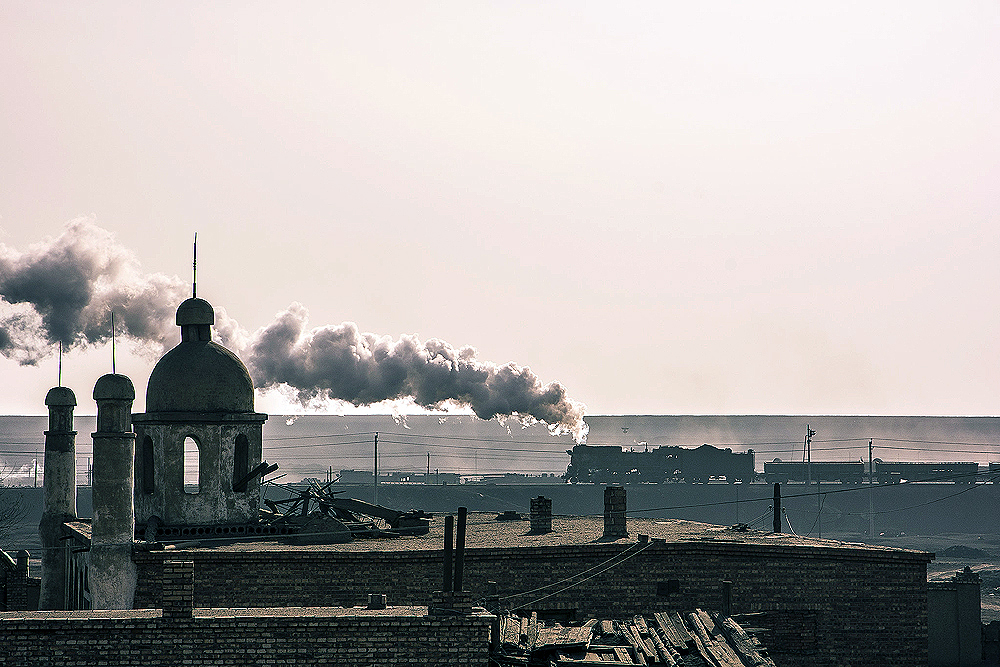 A steam locomotive in the background of an old city.