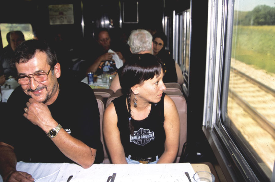 Woman seated at a dining car table looking out a window.