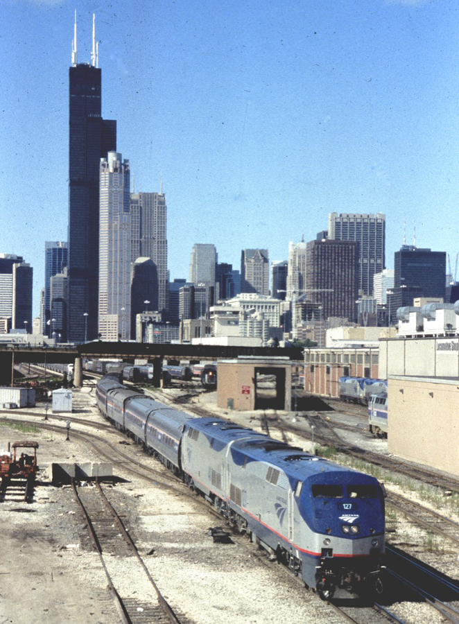 Amtrak passenger train on a bright and clear day with Chicago's skyline in the background.