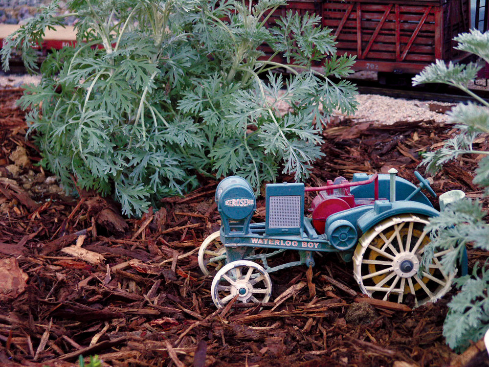 A vintage tractor model found at a yard sale fits in this garden railway scene.