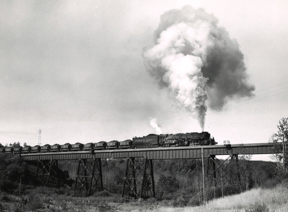 Articulated steam locomotive with freight train on bridge