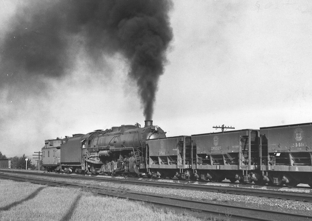 Steam locomotive pushing on rear of freight train