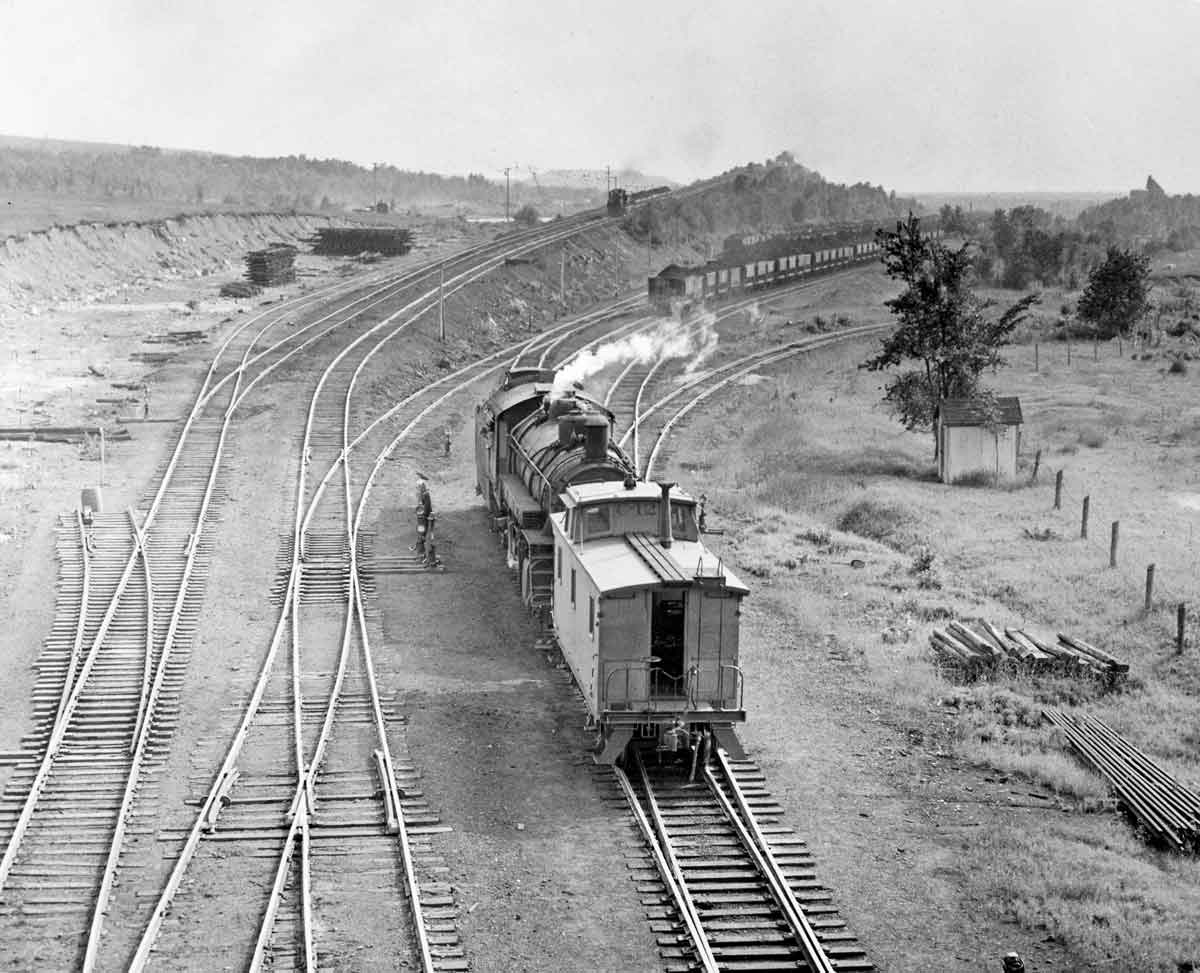 Overhead view of steam locomotive and caboose in freight yard