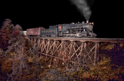 A freight train at night, a diesel at the turntable, a steamer in the shop, and other model railroad photos