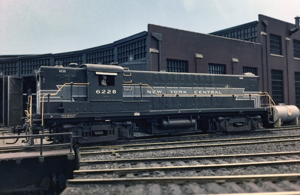 A diesel in New York Central’s two-tone gray lightning stripe scheme rolls onto a turntable