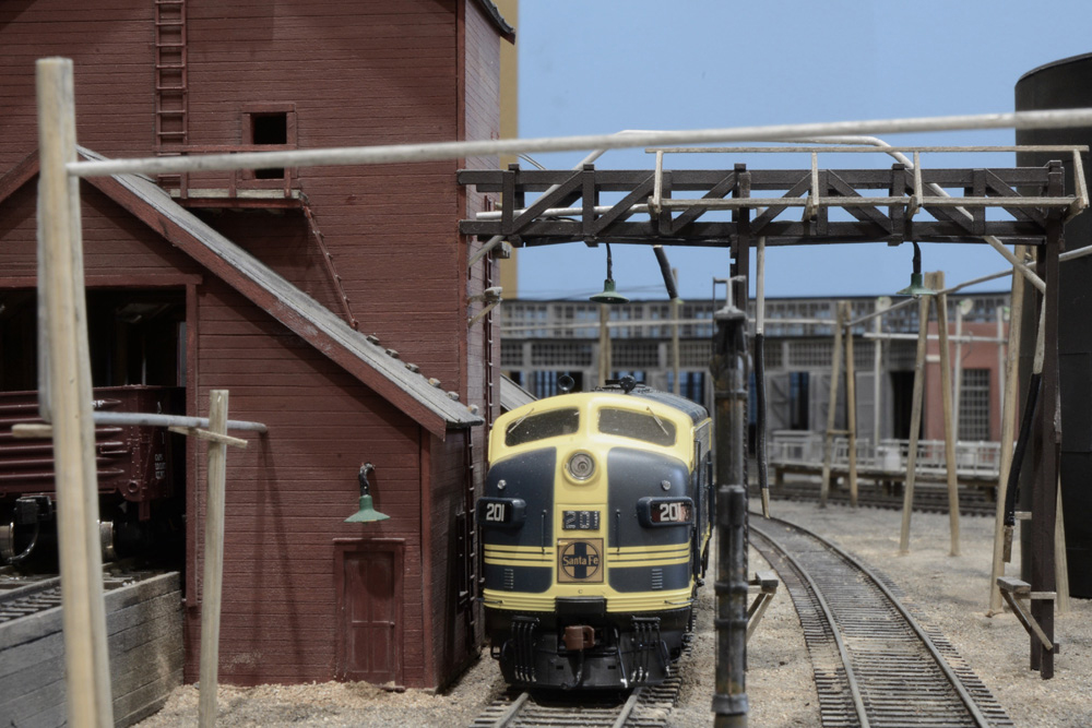 A blue-and-yellow Santa Fe EMD F3 diesel sits alongside a wooden sand bin