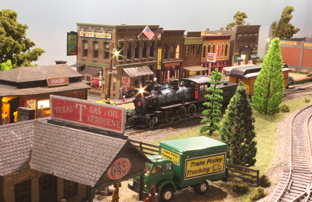 A well-preserved but old-fashioned steam locomotive pulls a combine into a small town