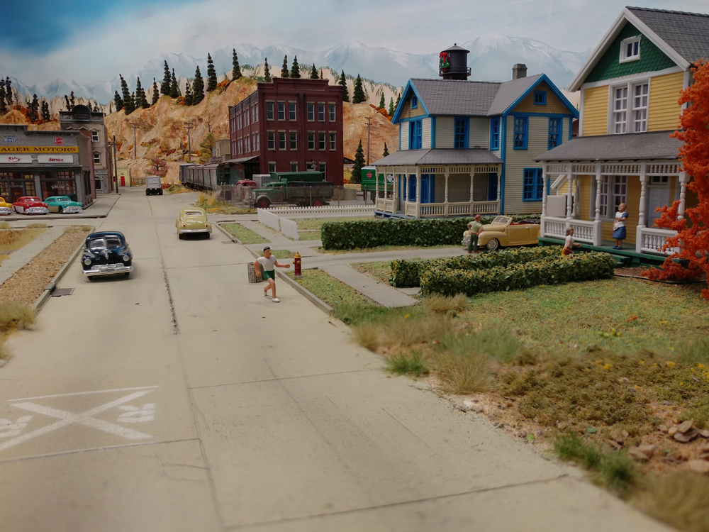 Concrete street with two, two-story wood-frame houses made from Walthers Cornerstone kits, Railway Express Agency warehouse in background